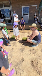 ニールさんが子どもたちを前にあぐらで説明している